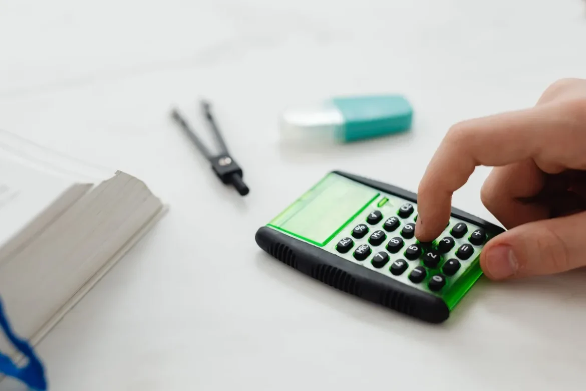 Mains tenant une fiche de paie imprimée avec calculatrice et stylo sur un bureau