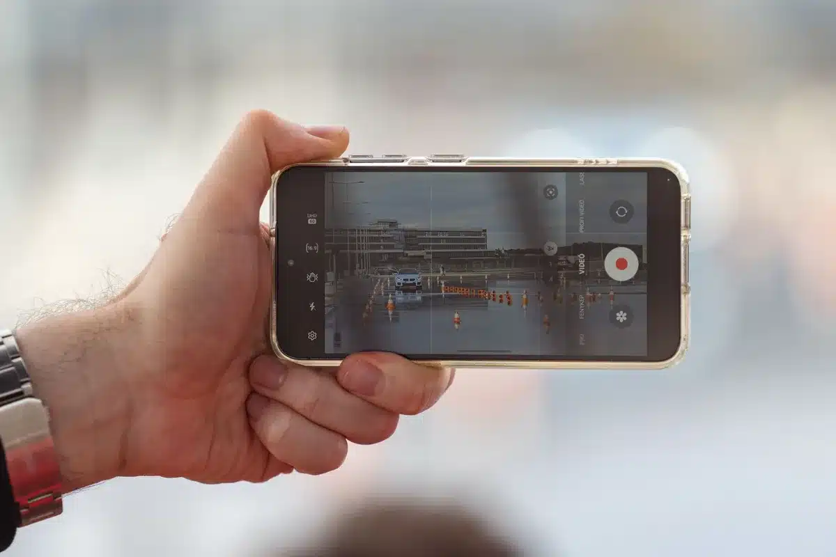 Mains tenant un téléphone pour documenter une scène en public, sans confrontation.