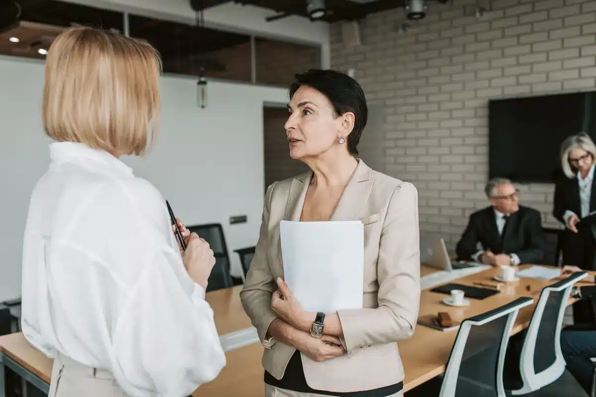 Deux collègues en conversation respectueuse dans un environnement professionnel neutre.