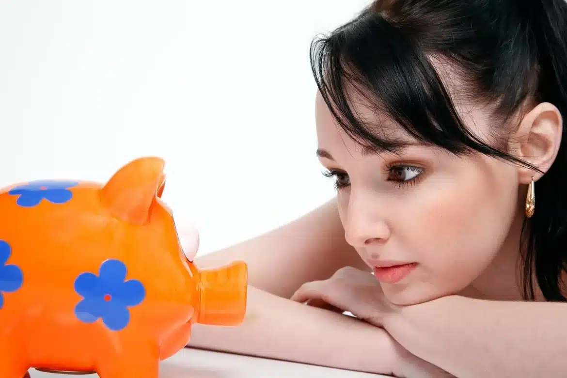 Main d'une personne versant des pièces régulièrement dans une tirelire, symbolisant l'investissement progressif et disci