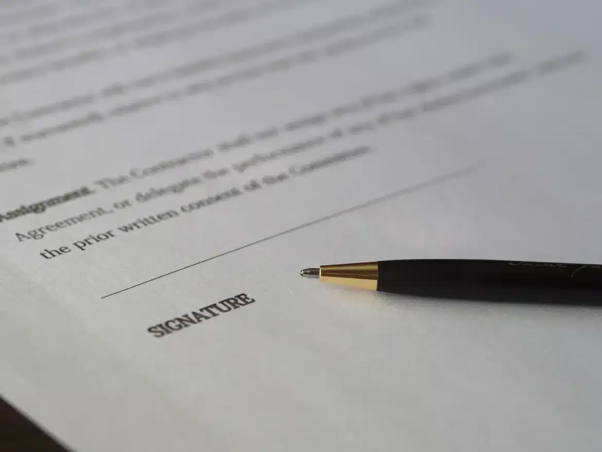 Mains remplissant un formulaire juridique sur un bureau administratif