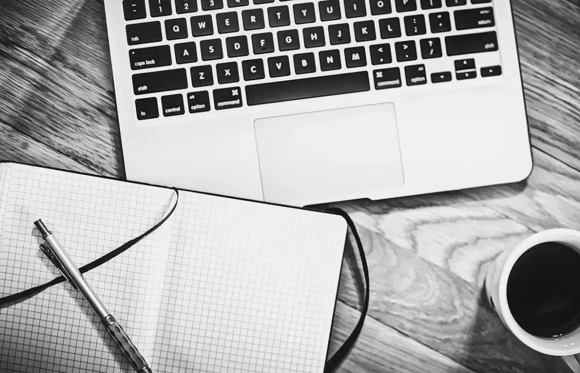 Bureau lumineux avec ordinateur portable, carnet et mains, création de site en cours