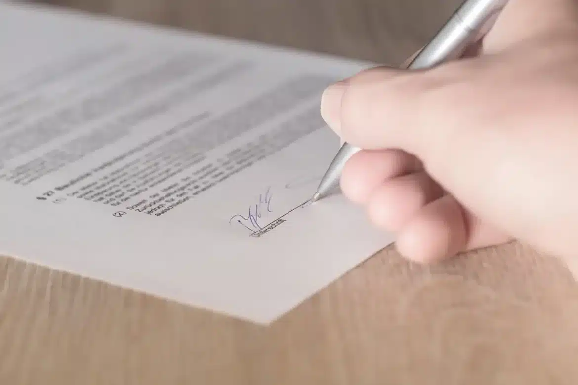 Bureau lumineux, mains anonymes feuilletant un contrat près d'un carnet