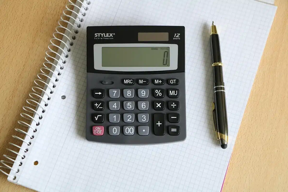 Calculatrice et fiches de paie sur un bureau lumineux pour illustrer le calcul de l'indemnité