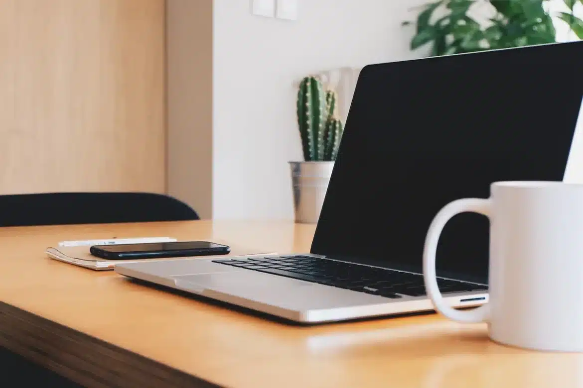 Bureau à domicile en pleine journée avec ordinateur et smartphone montrant une vidéo courte