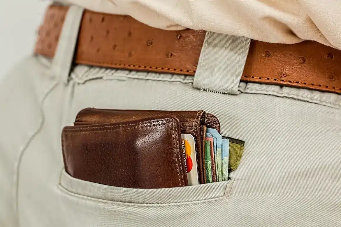 Client anonyme payant avec une carte sans marque devant des rayons de supermarché en plein jour